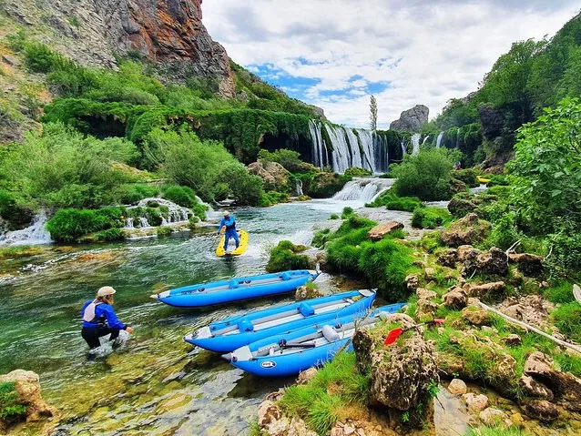 Des kayaks gonflables bleus flottent près des magnifiques cascades de la Zrmanja, avec un kayakiste.