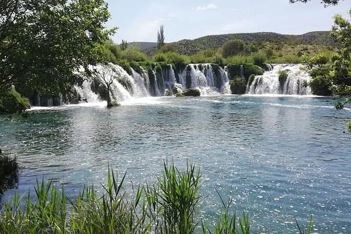 A beautiful view of the wide, multi-tiered Zrmanja Waterfalls cascading into clear water.